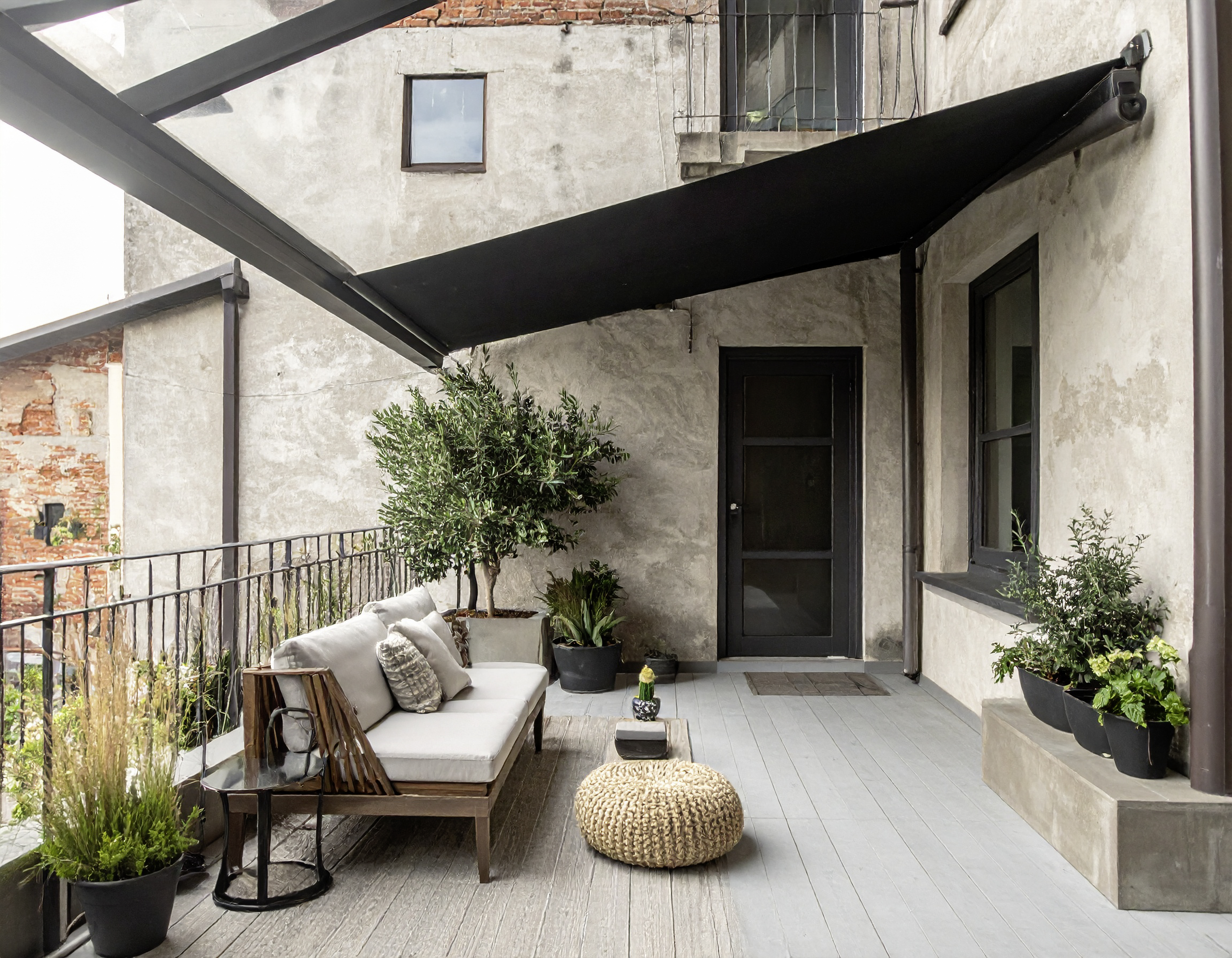 Gemütliche Terrasse mit Sofa, Pflanzen und moderner schwarzer Markise